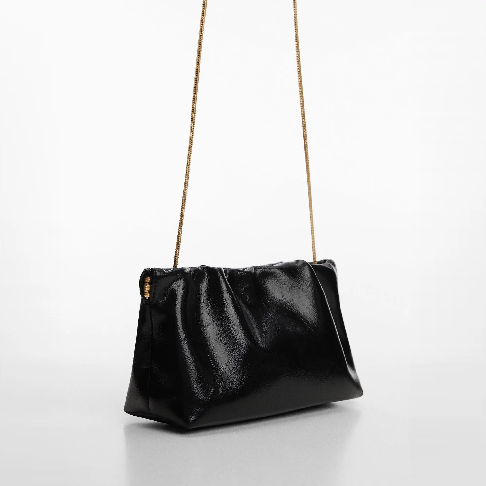 Sac à main en noir élégant avec une bandoulière en chaîne dorée et un design minimaliste